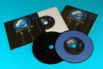 A premium vinyl CD set with custom colour Pantone blue printed discs with four tracks etched in the top vinyl grooves to match the tracks on the discs